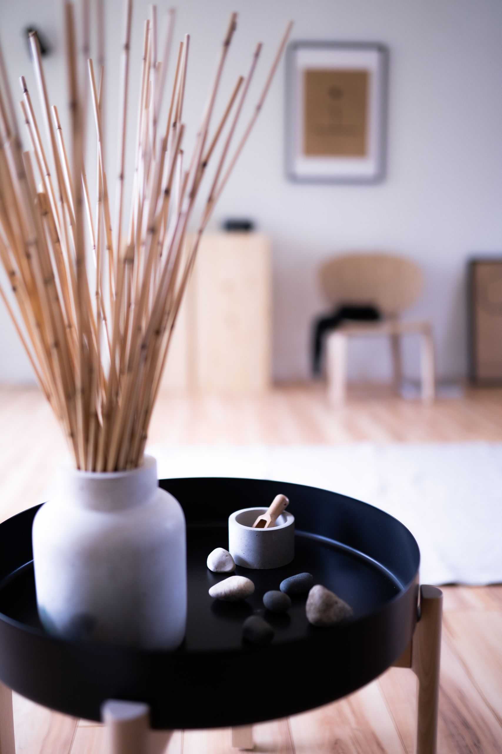 A modern Japandi-style interior featuring a round table with bamboo decor and a ceramic vase.